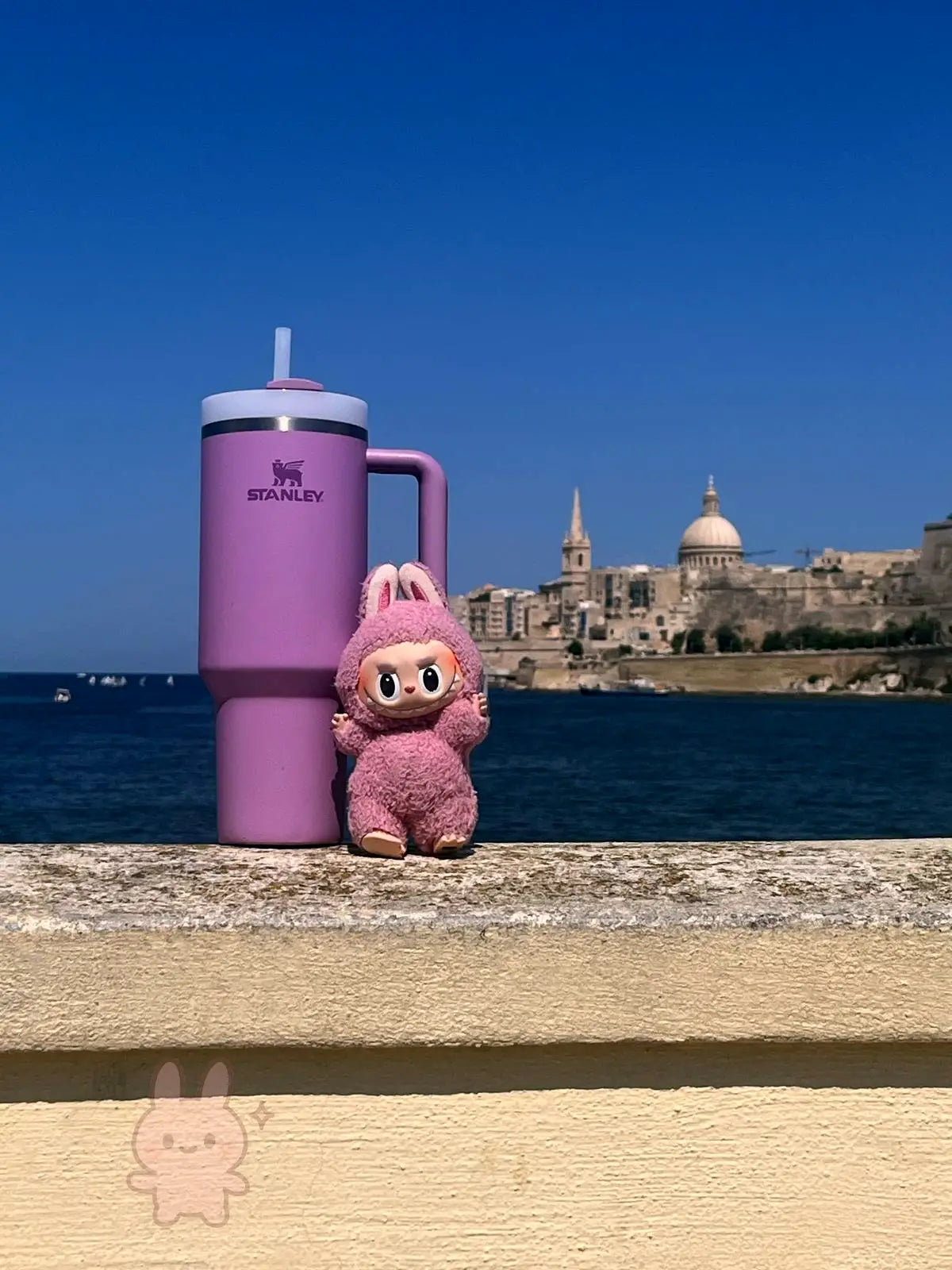 Pink Stanley Quencher and pink Labubu collectible by the sea in Malta