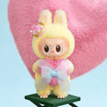 Toy figure with bunny ears and a bow tie on a pink heart background