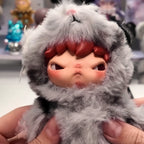 Hirono Road Journal Series Plush Doll Close-up of a plush toy with gray fur and red hair held by hands.