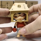 Hirono The Other One Small figurine with a house-shaped head held between fingers