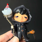 Hirono-monsters-carnival Figurine of a character in a black hooded outfit holding a small white ghost-like figure on a string.