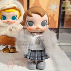 Baby Molly - Winter Fit Check Two dolls with large eyes and fur-lined outfits on a white surface.