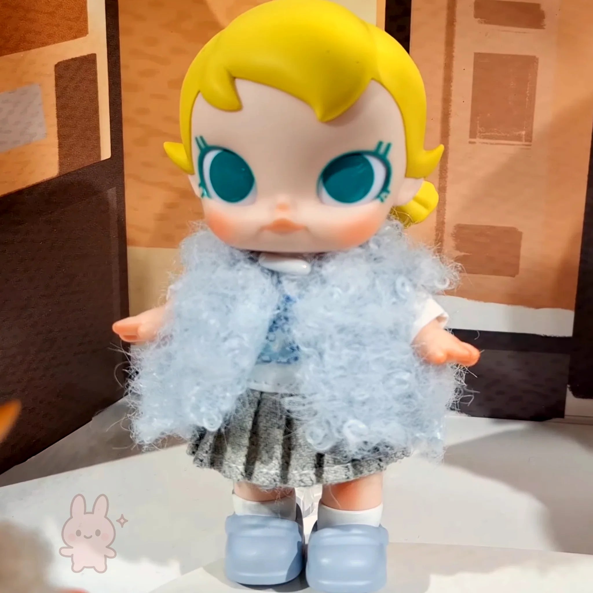Baby Molly - Winter Fit Check Toy figure with blonde hair and blue eyes wearing a light blue outfit with a fluffy texture.