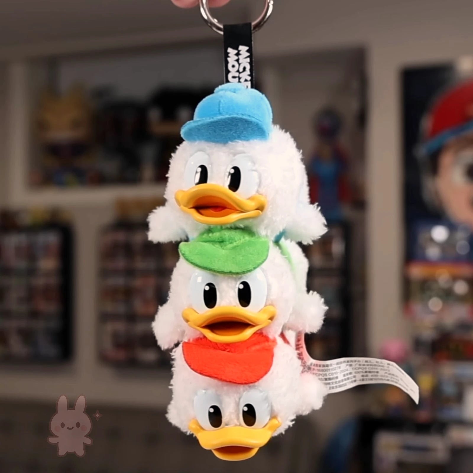 Plush keychain with three different colored hats on a blurred background