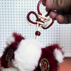 Pop-Mart-Have-a-good-run Close-up of a red and white keychain with fluffy details against a blurred background