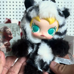 Pop-Mart-Have-a-good-run Plush toy with black and white fur held by a person, with a blurred background