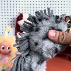 Pop-Mart-Have-a-good-run Close-up of a hand holding a gray hedgehog-shaped toy with a blurred background