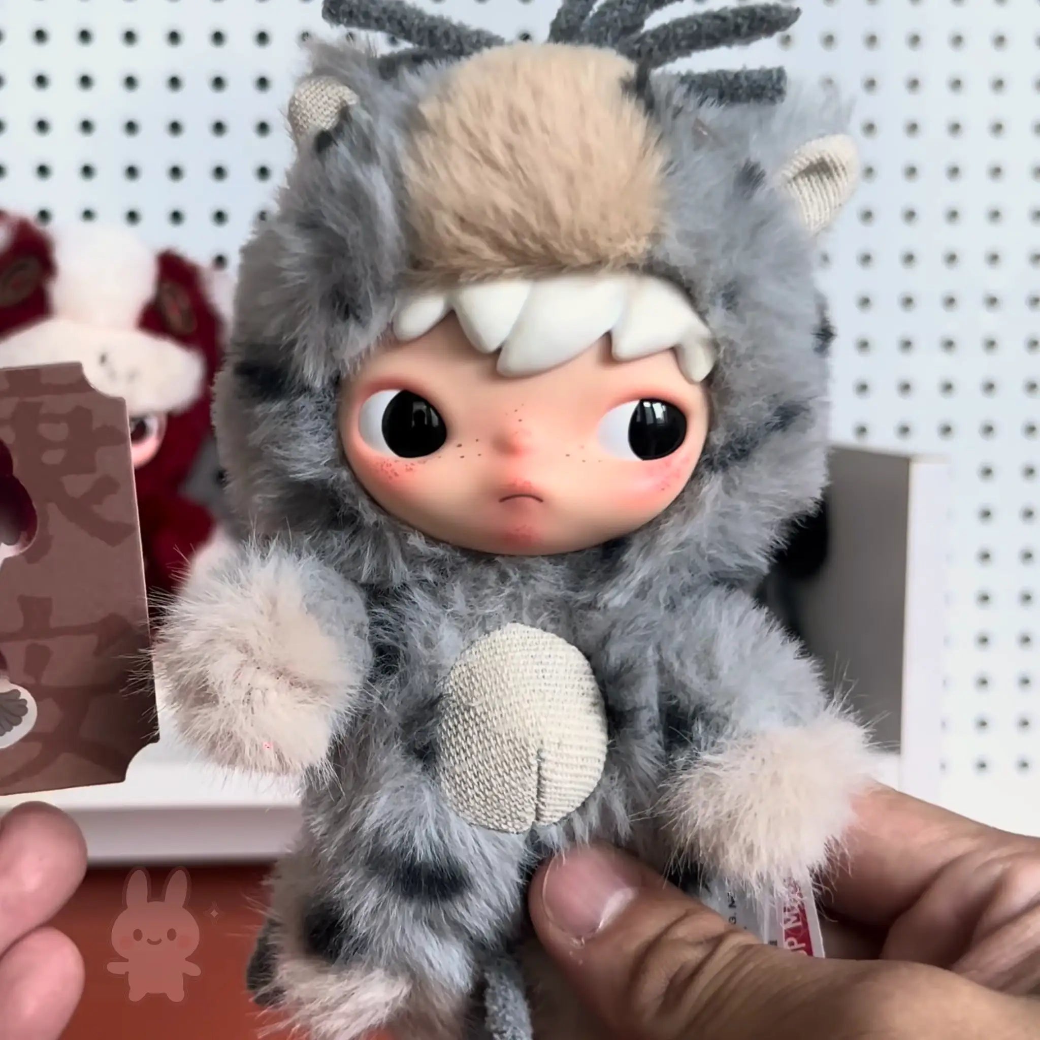 Pop-Mart-Have-a-good-run Plush toy with animal-like design held by a person against a white pegboard background