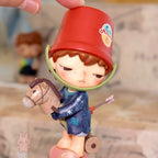 Pop Mart Hirono Echo Small figurine of a child with a red bucket on their head, holding a horse, with a blurred background.