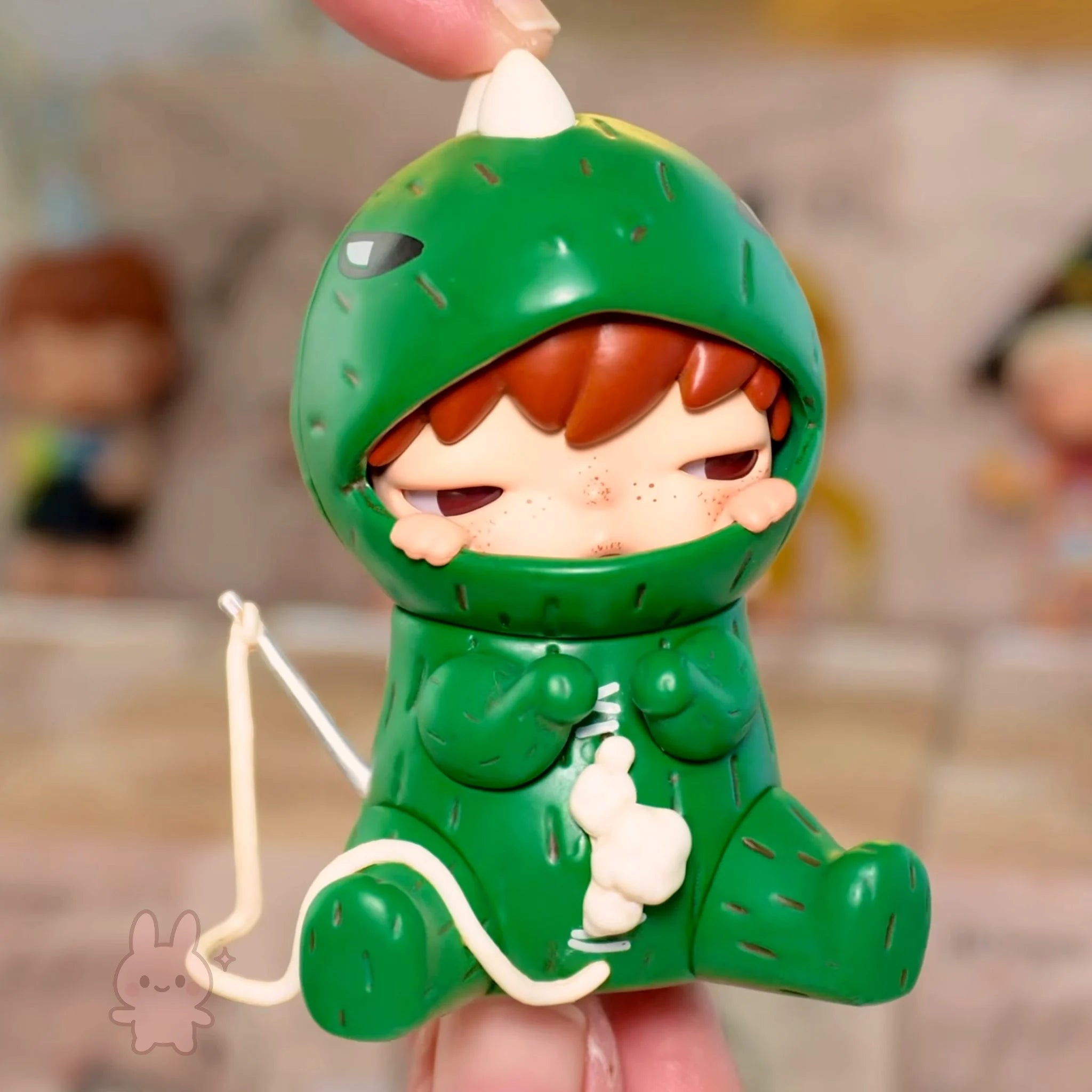 Pop Mart Hirono Echo Toy figure of a character in a green dinosaur costume holding a bow and arrow.