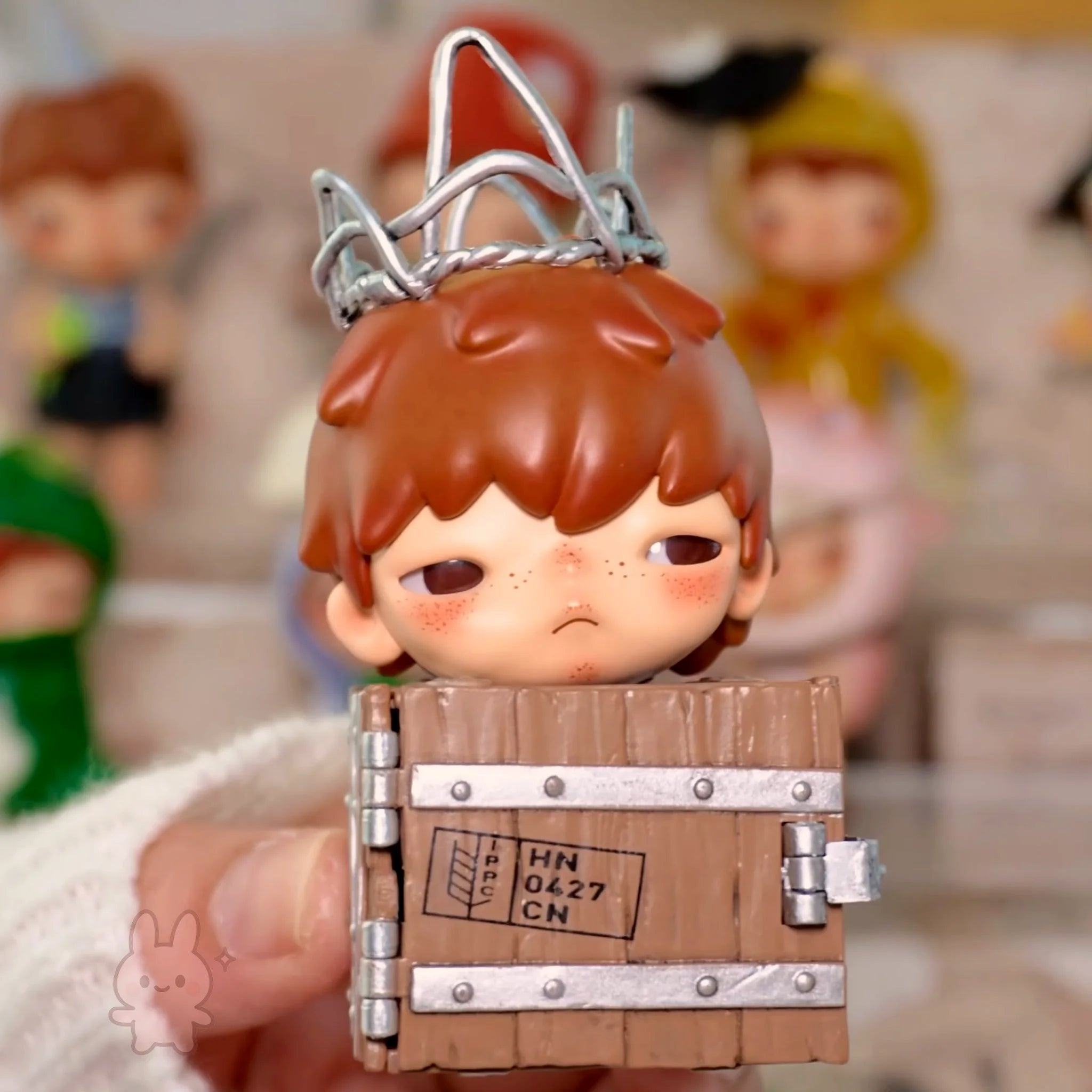 Pop Mart Hirono Echo Small figurine of a character with red hair and a wooden crate, held by a person.
