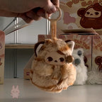 Pop Mart PUCKY Tap Tap Babies Plush keychain with cartoon character held by a hand, with boxes in the background