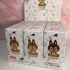 Pop Mart The Monsters 10th-anniversary Display of Pop Mart monster toy boxes with cartoon character on a pink background