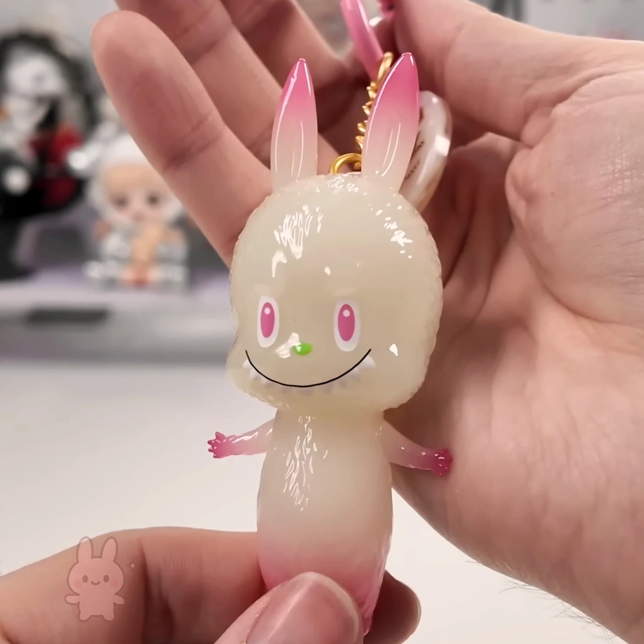 Pop Mart The Monsters 10th-anniversary Hand holding a cute rabbit-shaped keychain with a blurred background