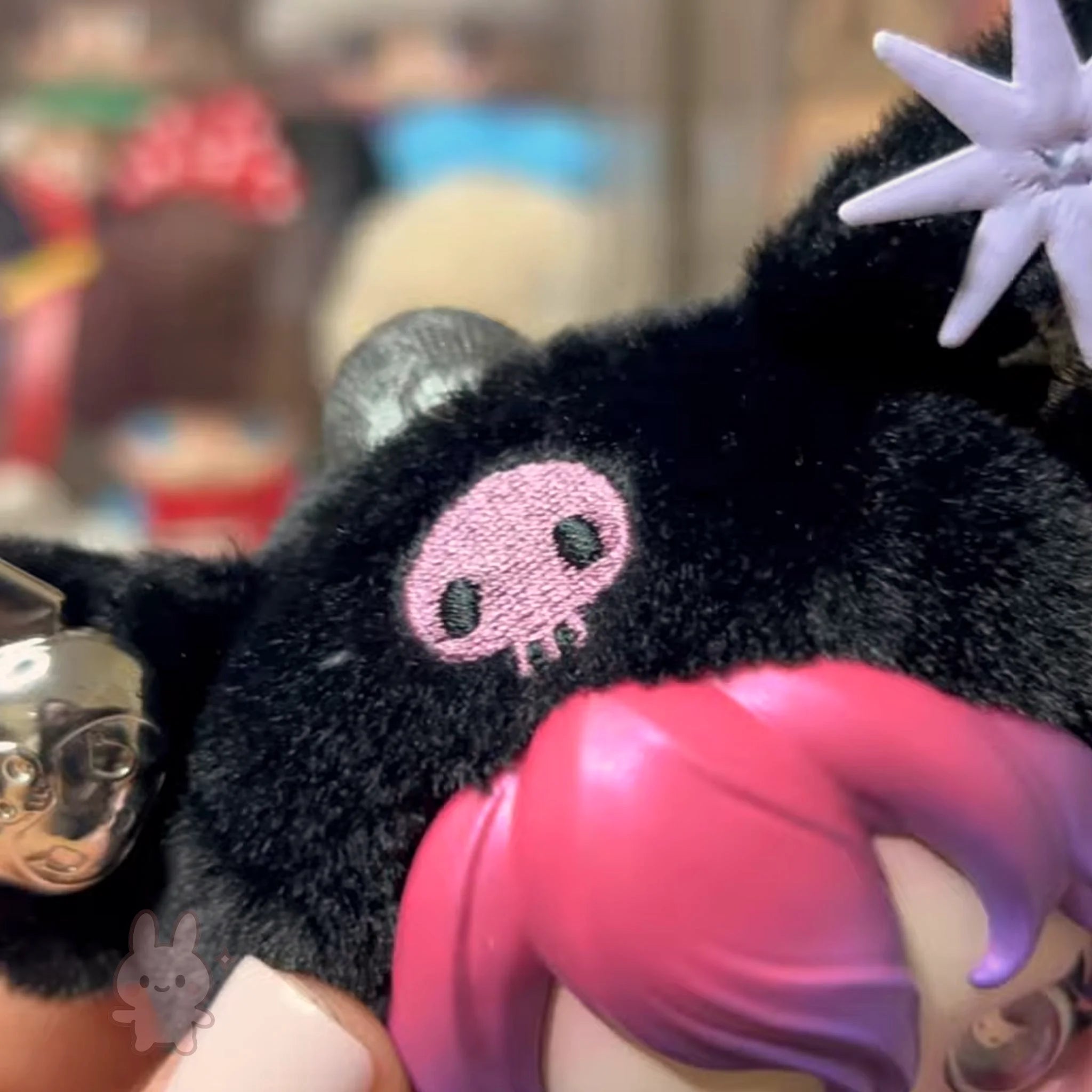 SKULLPANDA KUROMI Plush Close-up of a black plush toy with a pink skull design, held by a person.