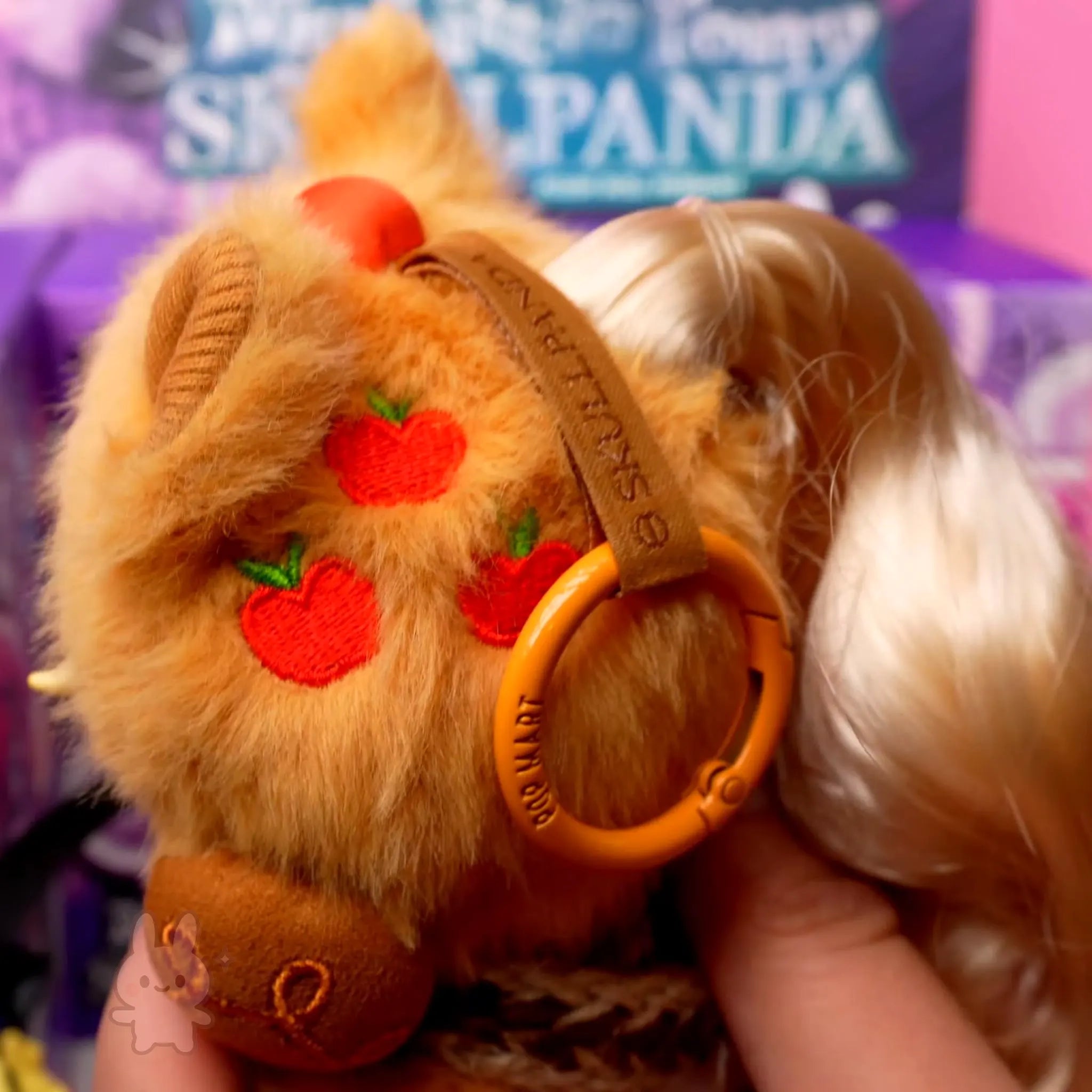 SKULLPANDA My Little Pony Plush Close-up of a plush toy with a headband featuring red apples, held against a blurred background.