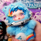 SKULLPANDA My Little Pony Plush Blue plush toy with rainbow accents held by a hand, with a colorful background.