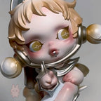 Skullpanda-the-feast-begins Close-up of a stylized figurine with blonde hair and gold accents on a plain background