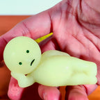 Smiski Light green plush toy resembling a baby dinosaur held in a hand against a blurred background