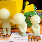 Three white Smiski figurines on a colorful book with visible text and images.