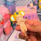 Sonny Angel hippers dreaming Hand holding a small figurine of a bear with yellow ears in a store setting