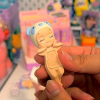 Sonny Angel hippers dreaming Small figurine of a baby in a hooded outfit held by a hand in a store setting.