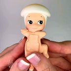harvest Small figurine held between fingers against a neutral background