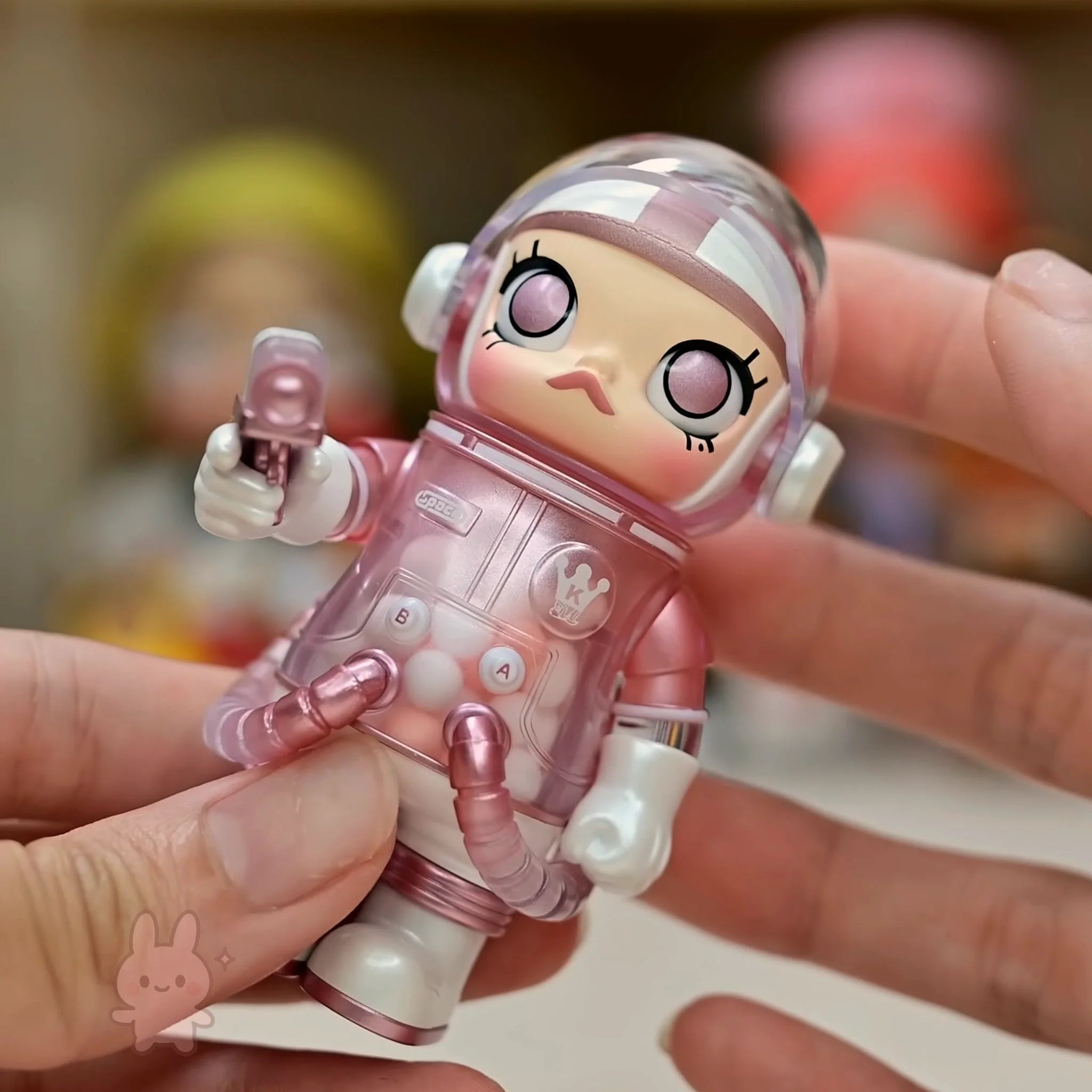 Space molly 100 series4 Toy figure of an astronaut in a pink space suit held by a hand.