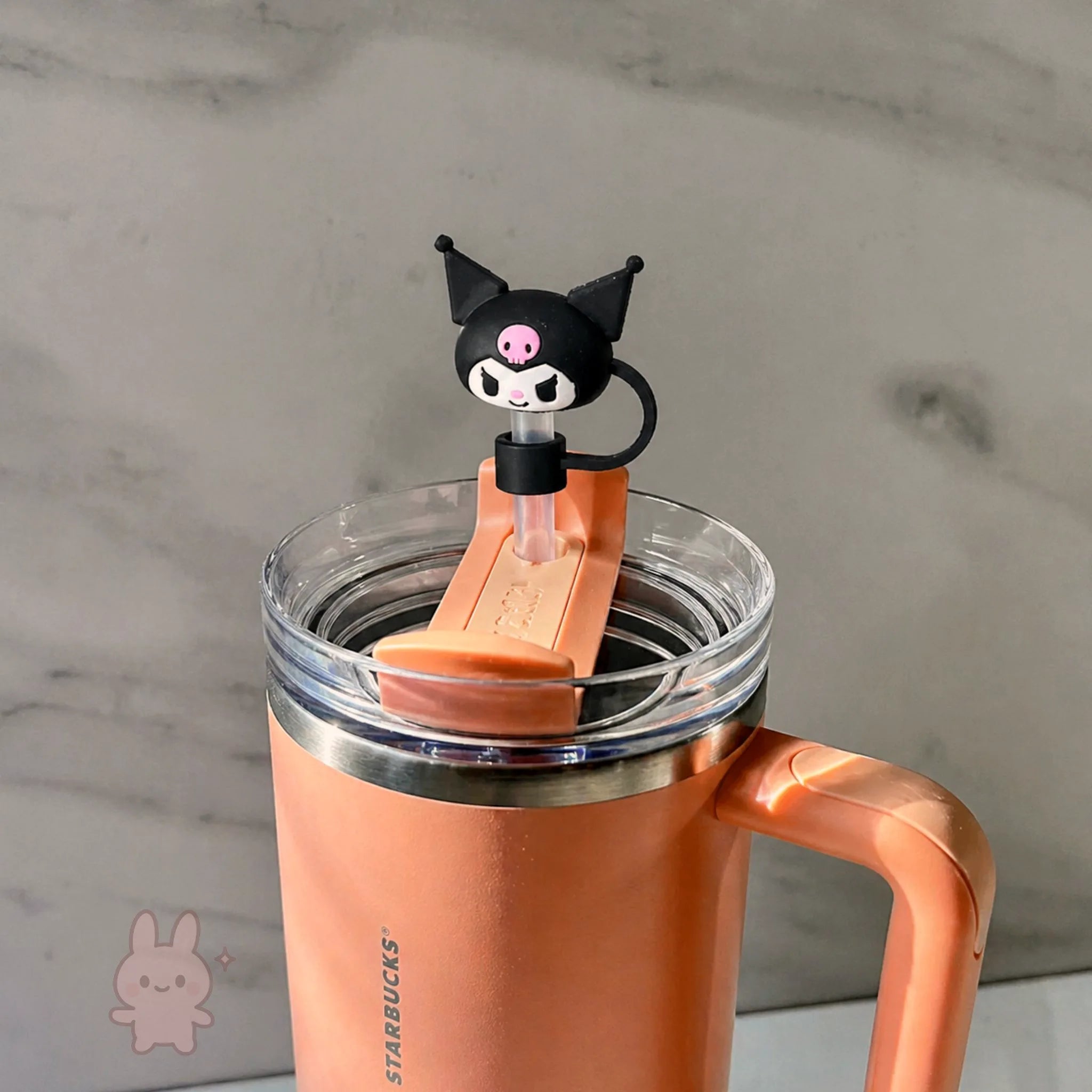 Orange Starbucks tumbler with a cartoon cat character on a marble surface