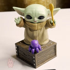 Star Wars Grogu Tiny But Mighty Toy figure resembling a character from a popular franchise on a wooden crate with a purple toy octopus.