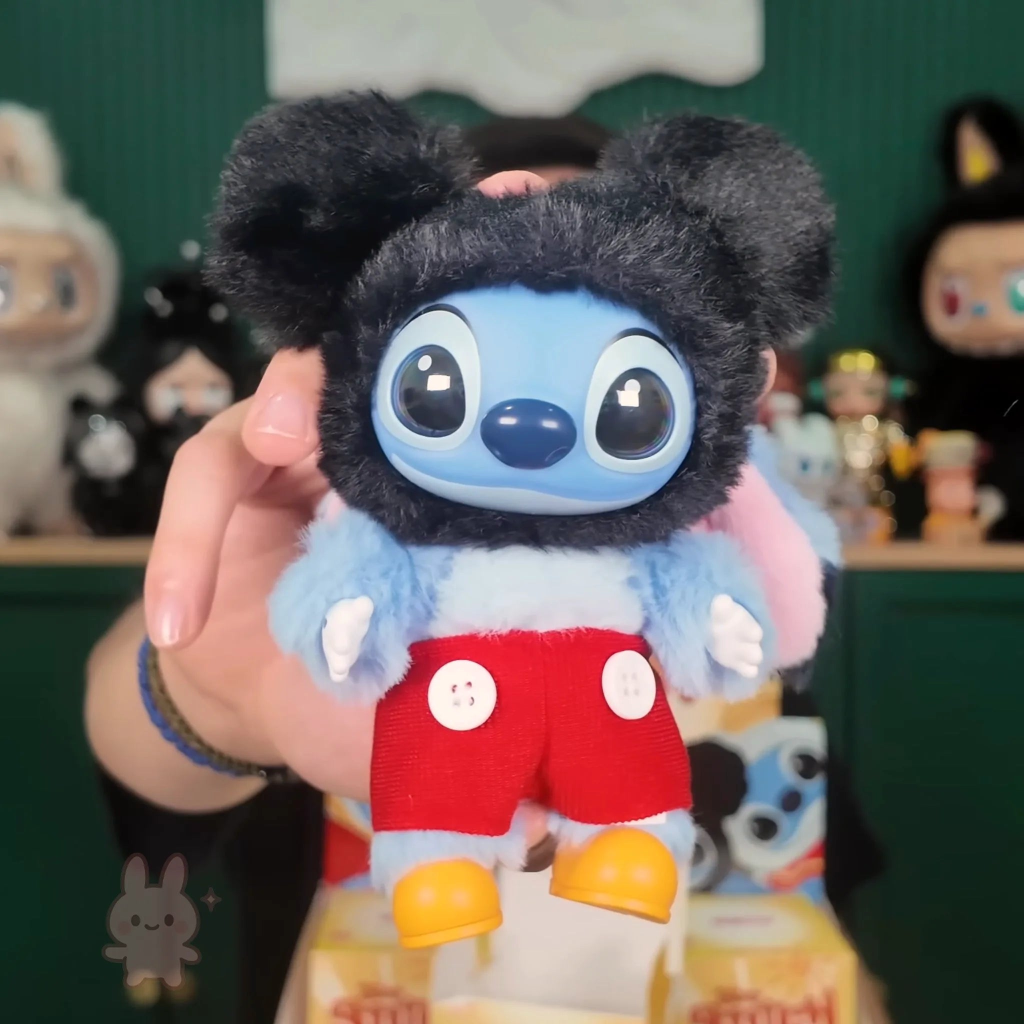 Stitch Adventure Plush toy resembling a character from a cartoon, held in front of a blurred background with other toys.