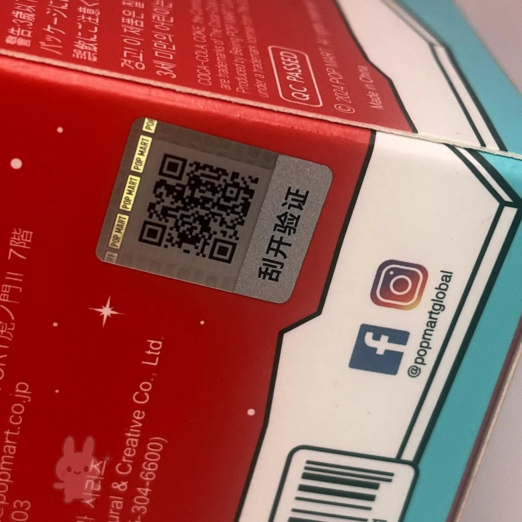 The Monsters Coca-Cola Close-up of a product packaging with QR code and social media icons.