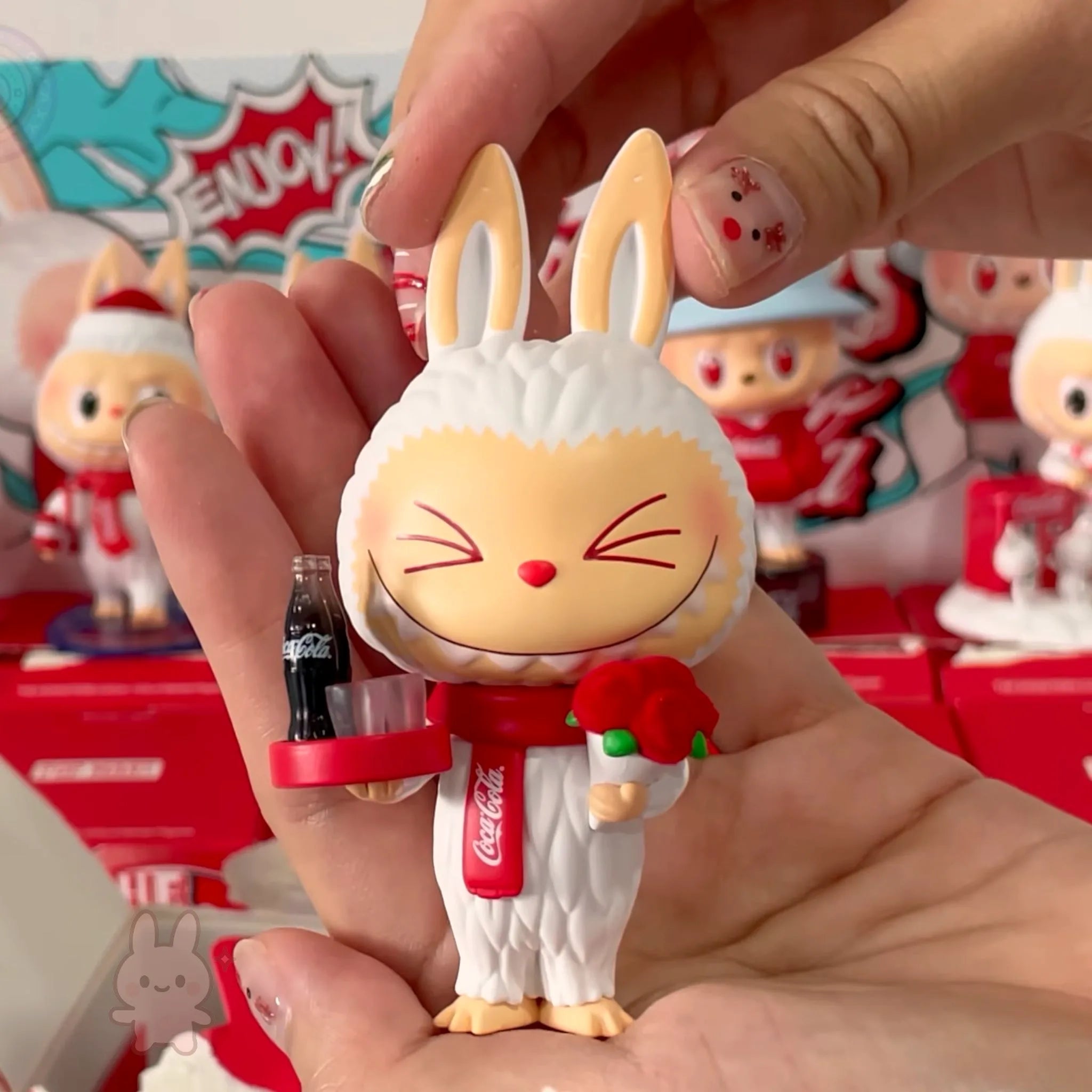 The Monsters Coca-Cola Figurine of a rabbit character holding a Coca-Cola bottle with a red ribbon, set against a colorful background.