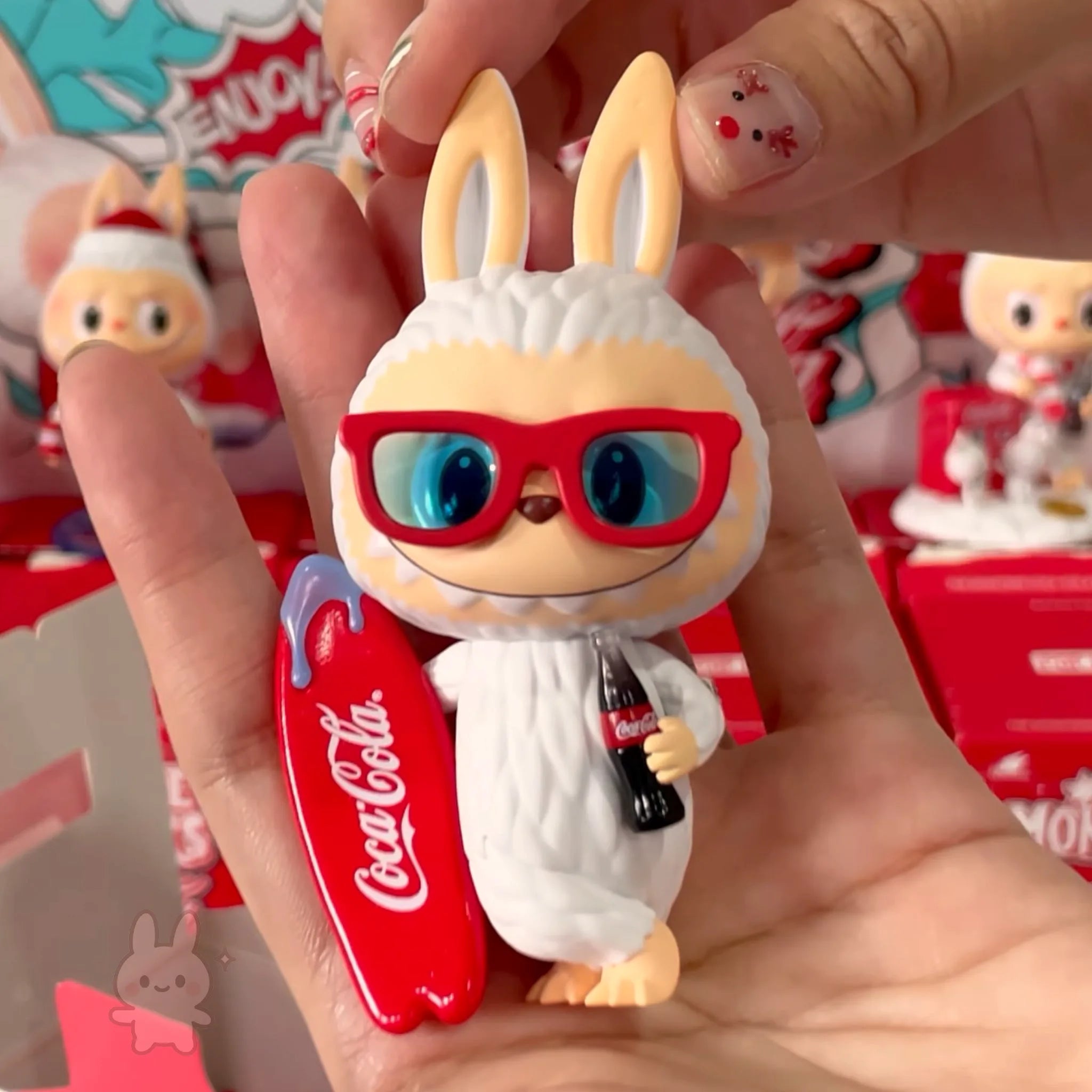 The Monsters Coca-Cola Toy figure of a character in a Coca-Cola costume held in a hand with a blurred background