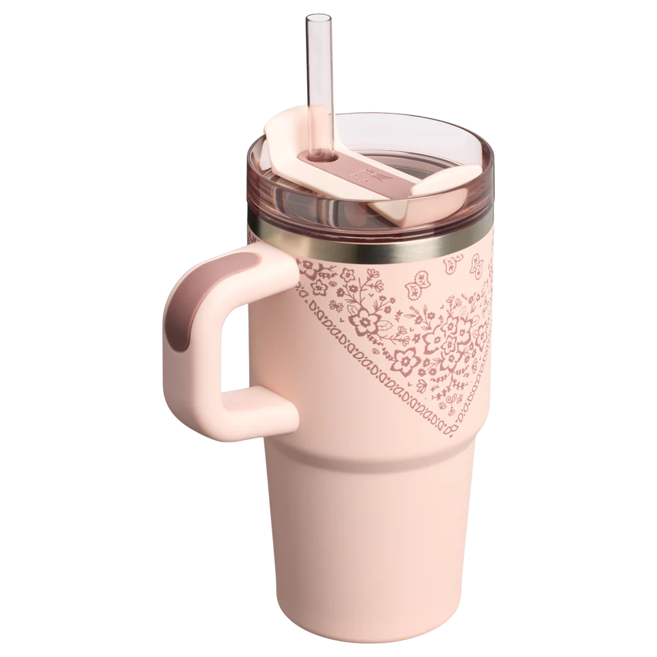 Pink tumbler with floral pattern and handle on a white background