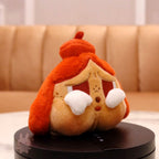 Plush toy resembling a character with an orange hat on a black stand against a beige background