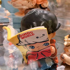 dimoo-the-missing-day Figurine holding a 'DIMOO WORLD' book with a cartoon character on a blurred background