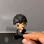 hirono Small figurine of a character with black hair and a red bow tie held by a hand against a gray background.