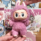 Labubu – Exciting Macaron Vinyl Face – pink plush toy with bunny ears held by a hand against a colorful background