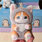 mofusand fluffy kittens Plush cat-shaped keychain held in a hand with a blurred background