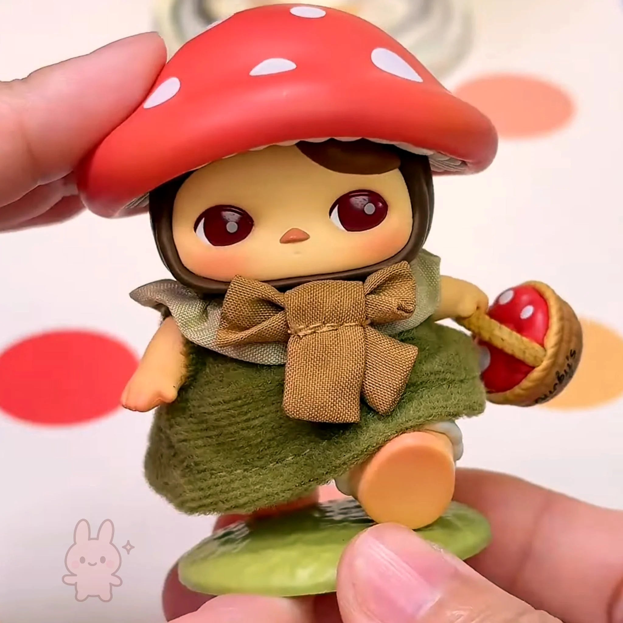 pucky faries market Toy figure with a red mushroom hat held by a hand against a colorful background