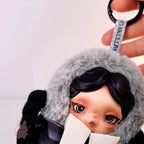 skullpanda Keychain with a doll-like figure wearing a fur coat, held by a hand against a light background.