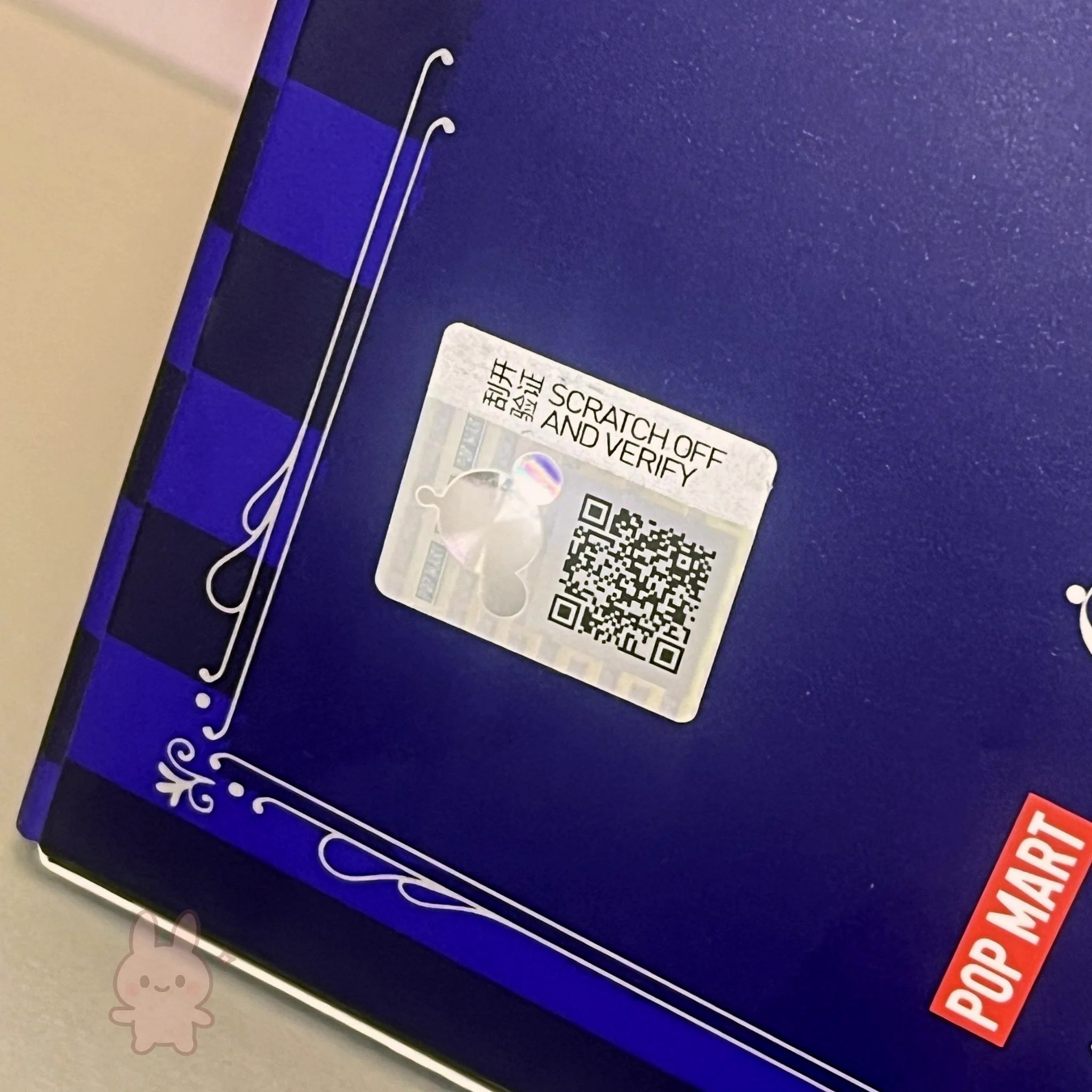 skullpanda Scratch-off card with QR code on a blue surface with Pop Mart branding.