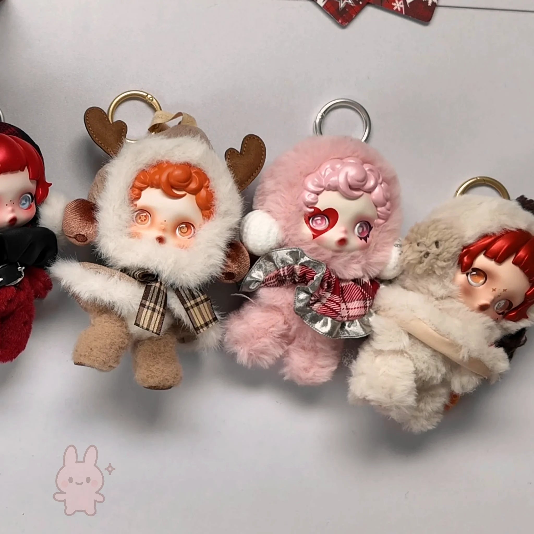 skullpanda Four plush keychains with cartoon-like faces on a light gray background