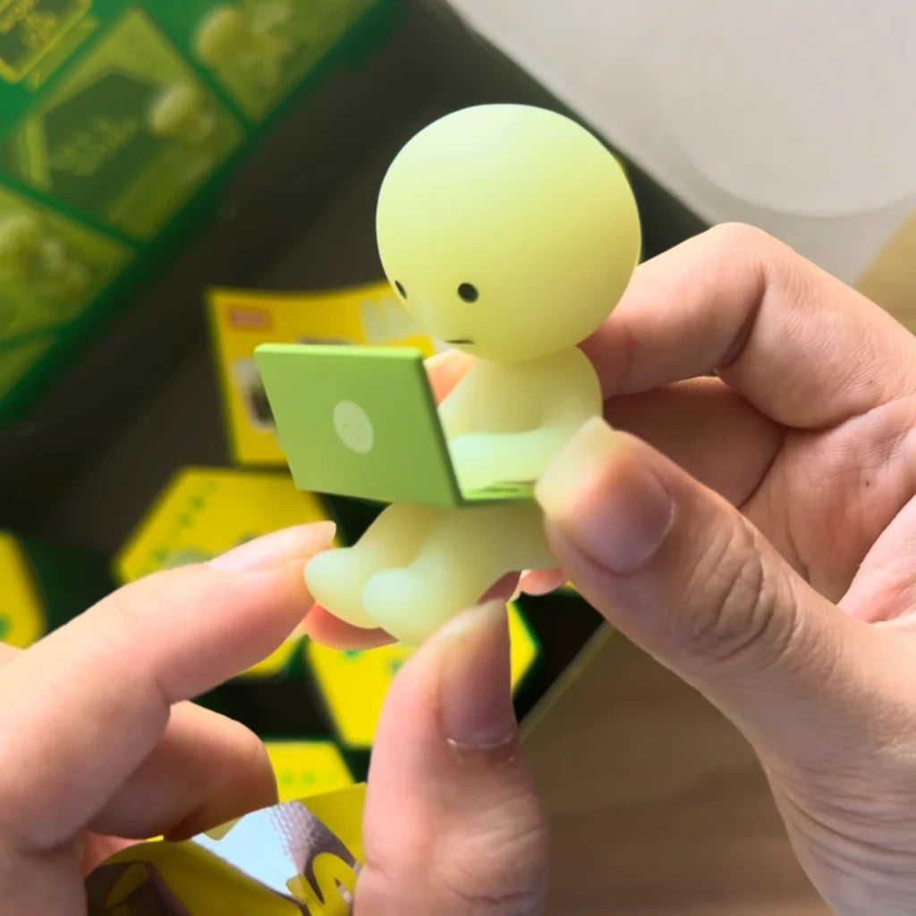 SMISKI Researching figure from the Work Series sitting with a green laptop, held in hand