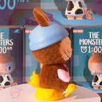 the-monster-1am-series Toy figure with a blue hat and brown body in front of display boxes.