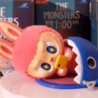 the-monster-1am-series Toy figure with a pink hood and blue mouth, set against a dark background with text.