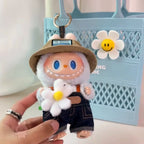 Labubu Plush keychain of a character with a hat and overalls, holding a flower, against a light blue background.