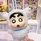 shinchan Plush toy of an animated character in a white outfit with a surprised expression, held in front of colorful packaging.