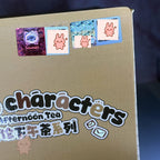 Cardboard box with 'characters Afternoon Tea' text and colorful stickers on a dark background